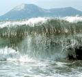 Large wave in front of mountains