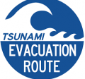 Blue round tsunami evacuation route sign with white ocean wave