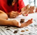 close up of woman in red shirt stacking coins in another person's hand