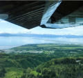 Aerial photo looking south over Homer bluffs towards the City of Homer, airport and the Homer Spit on a blue sky, summer day.