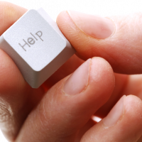 hand holding a computer keyboard key that says Help