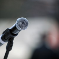 Close up of a microphone being held up by a black microphone stand.