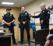 Two uniformed police officers standing with a Police Chief, also in uniform.