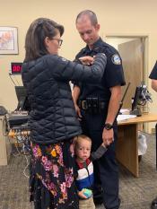 Officer Stock getting his new badge pinned on by his wife.