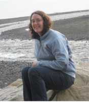 Photo of missing person, Anesha "Duffy" Murnane sitting on a boulder at the beach.