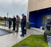 Five people standing in front of Homer's new Police Station cutting a blue ribbon.