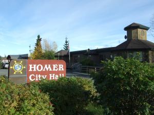 Homer City Hall sign on Pioneer Avenue with City Hall in background