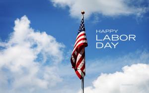 American Flag hanging on pole in blue sky with white puffy clouds