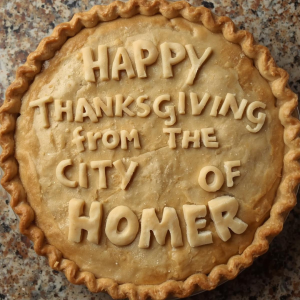 The top of a baked pie with fluted edges and dough lettering saying Happy Thanksgiving from the City of Homer