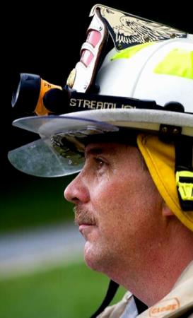 Profile picture of man wearing fire fighter's helmet.