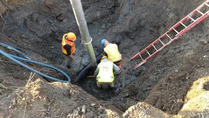 Three Homer Public Works Department personnel work in a deep waterlogged hole near Lake street to fix a broken water main pipe.