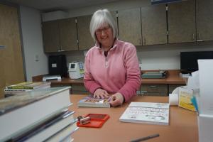 A volunteer prepares a book to be ready for the shelves by putting the plastic covering on its sleeve. 