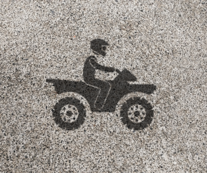 Black stencil of ATV rider wearing a helmet on gray background