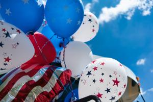 Close up image of white and blue balloons with stars on them tied together with a blue sky background.