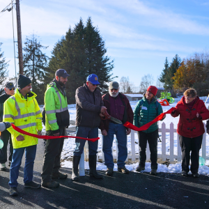 Line of people people behind a red ribbon as two men cut the ribbon to re-open Bayview Park.