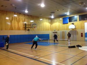People playing pickleball in a gymnasium.