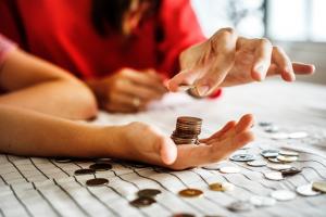 close up of woman in red shirt stacking coins in another person's hand