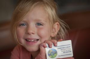 young child holding library card