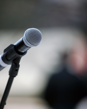 Close up of a microphone being held up by a black microphone stand.