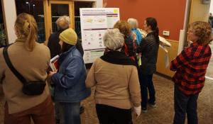 Eight people standing around a display board that explains the relationship of zoning regulations to a comprehensive plan.