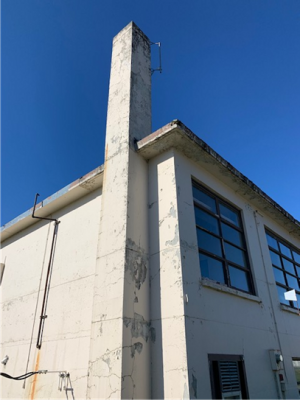 The corner of an old concrete building with a blue sky background