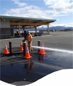 Public works employee with four orange cones flushing water from a fire hydrant in port and harbor