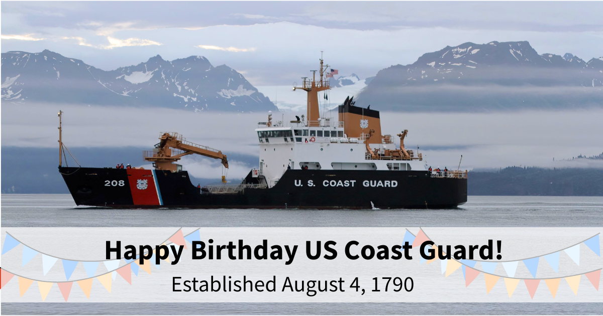 The Coast Guard Cutter Aspen in Kachemak Bay with mountains and a glacier in the background on a gray cloudy day.