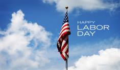 American Flag hanging on pole in blue sky with white puffy clouds