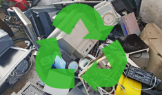 Pile of old electronics on damp concrete ground with the three green arrow recycling logo superimposed.