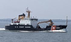 The USCG cutter Aspen on the waters of Kachemak Bay with cloudy, gray skies in the background