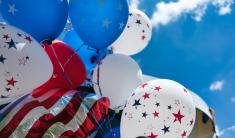 Close up image of white and blue balloons with stars on them tied together with a blue sky background.