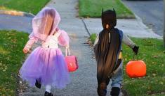 Trick-or-Treat Kids Two kids walking down sidewalk in Halloween costumes and holding treat bags shaped like jack-o-lanterns.