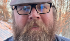 A bearded man with glasses and a wool hat