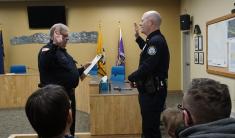With right hands raised, outgoing police chiff stands and administers oath of office to the new, incoming police chief.