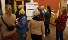 Eight people standing around a display board that explains the relationship of zoning regulations to a comprehensive plan.