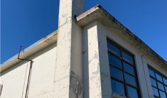 The corner of an old concrete building with a blue sky background