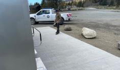 City staff person standing on concrete pad in front of a mobile restroom unit with a white pickup truck parked in the background